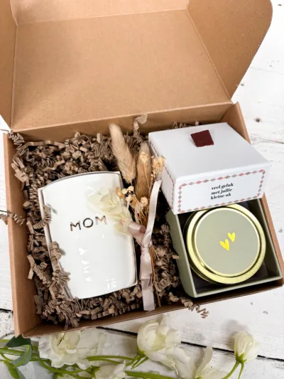 In deze giftbox vind je: Keramieken vaasje met MOM Kaarsje in blik met hartjes Cadeaudoosje Veel geluk met jullie kleine uk Decoratieve droogbloemetjes 🎁 Rechtstreeks naar de mama-to-be laten bezorgen? Laat de giftbox direct naar de ontvanger sturen en voeg een persoonlijke boodschap toe. Wij pakken het cadeau met zorg in, zodat het helemaal klaar is om iemand mee te verrassen. Perfect als zwangerschapscadeau, babyshower cadeau, felicitatie zwangerschap of cadeautje voor een aanstaande moeder.